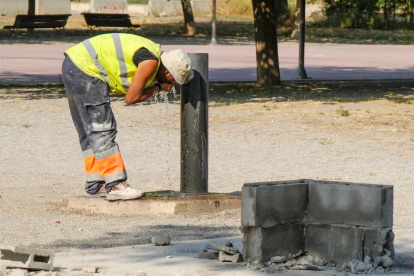 Un trabajador se refresca en una fuente de un parque de Lleida, este viernes en que todas las comarcas de Cataluña.