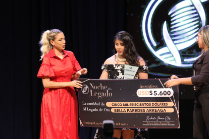 Bella Paredes recibiendo de manos de la prefecta Susana González el primero al Legado de Oro y dinero en efectivo.