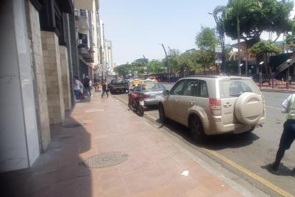 A pocos metros de los carros estacionados se encuentra una señalética de no parquear.