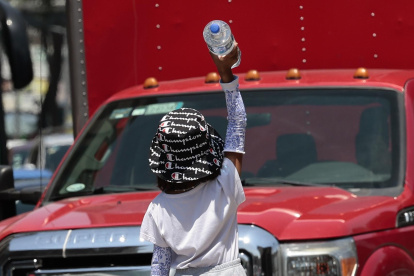 San Salvador. Un menor traslada mercadería entre los vehículos estacionados en una esquina de esta capital centroamericana.