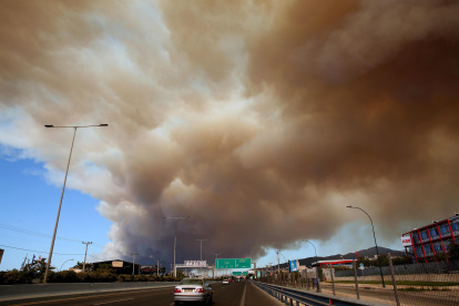 Un espeso humo cubre la carretera nacional en Atenas debido a un incendio forestal que estalló en una zona de tierras de cultivo y bosque en Varnavas, región de Ática, Grecia.
