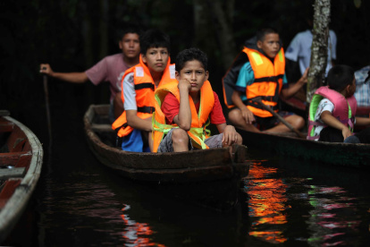 Un grupo de niños en canoas dirigiéndose a un vivero por el rio Itaya, en Iquitos (Perú).