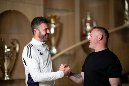 Michael Carrick (i) y Wayne Rooney, leyendas del United, se saludan.