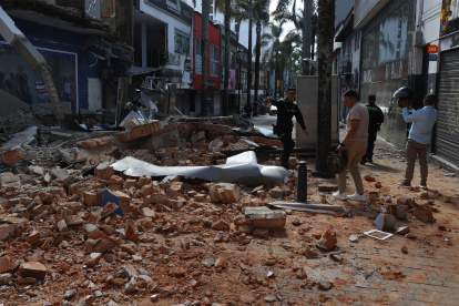Personas caminan frente a una edificación afectada tras un fuerte temblor este lunes, en Manizales (Colombia)