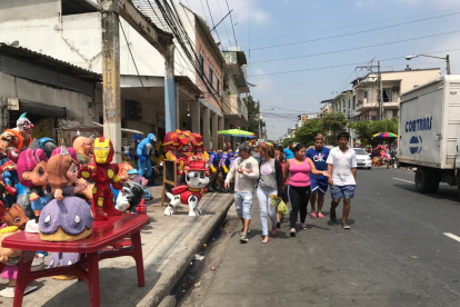 Los visitantes de la calle 6 de marzo caminan por la calzada, cerca de los carros.