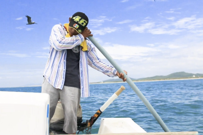 Práctica. En su labor diaria, el pescador escucha el sonido de los peces a través de un tubo plástico.