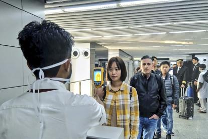Un hombre usa una cámara termográfica para controlar la cabeza de las personas en el Aeropuerto Internacional Netaji Subhash Chandra Bose en Kolkata, siguiendo las recomendaciones del Ministerio de salud.
