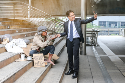 Empresario tomándose foto con mendigo.