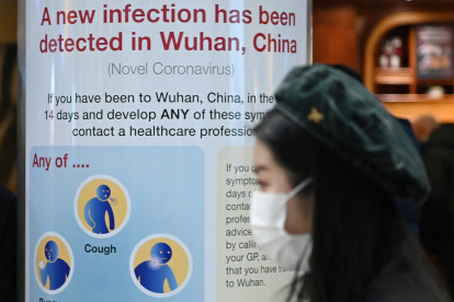 A woman wearing a face mask passes a Public Health England sign, warning passengers arriving on flights into the UK, that a virus, Coronavirus, has been detected in Wuhan in China, at Terminal 4 of London Heathrow Airport in west London on January 28, 2020. - Chinese President Xi Jinping said Tuesday the country was waging a serious fight against the "demon" coronavirus outbreak and pledged transparency in the government"s efforts to contain the disease. (Photo by DANIEL LEAL-OLIVAS / AFP)
