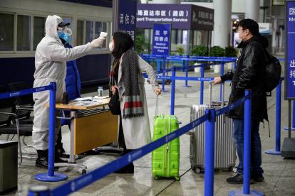 Personal de seguridad verifica la temperatura de los pasajeros que llegan al Aeropuerto Internacional de Shanghai.