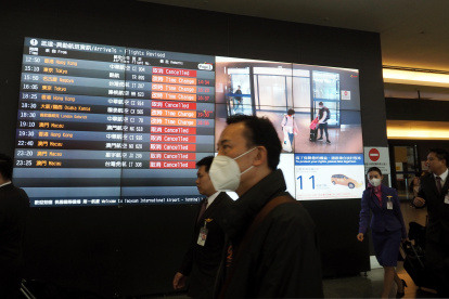 Pasajeros llegan al aeropuerto internacional de Taoyuan en la ciudad de Taoyuan, Taiwán, usan protección para evitar la propagación del coronavirus.