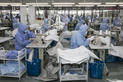 (FILES) This file photo taken on February 8, 2020 shows workers producing protective clothing at a factory which previously produced suits and sportswear and switched production for the fight against the deadly COVID-19 coronavirus, in Wuxi in China"s eastern Jiangsu province. - A diaper manufacturer in eastern China was closed for the Lunar New Year holiday when it heard from officials that China needed vast amounts of masks to fight the virus epidemic and factories needed to chip in, and in just over two days converted a manufacturing line in Fujian province to make face masks. (Photo by STR / AFP) / China OUT / TO GO WITH China-health-virus-manufacturing,FOCUS by Beiyi SEOW