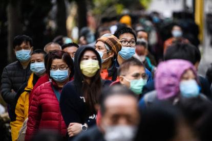 People wearing facemasks as a preventative measure following a coronavirus outbreak which began in the Chinese city of Wuhan, line up to purchase face masks from a makeshift stall after queueing for hours following a registration process during which they were given a pre-sales ticket, in Hong Kong on February 5, 2020. - The new coronavirus which appeared late December has claimed nearly 500 lives, infected more than 24,000 people in mainland China and spread to more than 20 countries. (Photo by Anthony WALLACE / AFP)