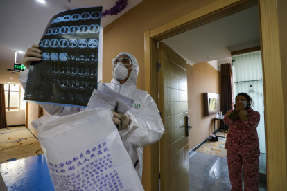 This photo taken on February 3, 2020 shows a doctor looking at a lung CT image while making his rounds at a ward of a quarantine zone in Wuhan, the epicentre of the new coronavirus outbreak, in China"s central Hubei province. - The number of total infections in China"s coronavirus outbreak has passed 20,400 nationwide with 3,235 new cases confirmed, the National Health Commission said on February 4. (Photo by STR / AFP) / China OUT