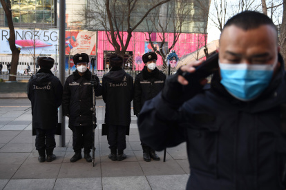 Security guards wearing protective face masks, amid concerns of the COVID-19 coronavirus outbreak, patrol in a shopping area in Beijing on February 17, 2020.   The death toll from China"s COVID-19 coronavirus epidemic jumped to 1,770 after 105 more people died, the National Health Commission said on February 17. More than 70,500 have now been infected nationwide by the virus, which first emerged in December in central Hubei province before spreading across the country. / AFP / GREG BAKER

 CHINA-HEALTH-VIRUS