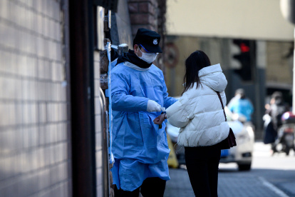 A security guard wearing a protective facemask checks the temperature of a woman before she enters a hospital in Shanghai on February 18, 2020.   The World Health Organization has warned against a global over-reaction to the new coronavirus epidemic following panic-buying, event cancellations and concerns about cruise ship travel, as China"s official death toll neared 1,900 on February 18.
 / AFP / NOEL CELIS

 CHINA-HEALTH-VIRUS
