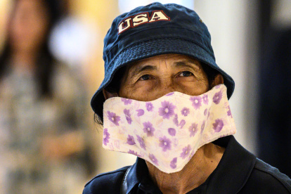 A shopper, wearing a protective facemask amid fears over the spread of the COVID-19 coronavirus, walks in a store in Bangkok on February 17, 2020. (Photo by Mladen ANTONOV / AFP)
