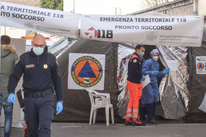 Piacenza. Dos profesionales de la salud que usan trajes protectores y máscaras de atención médica frente a la unidad médica avanzada construida fuera de la sala de emergencias del hospital local para hacer frente a la emergencia del coronavirus