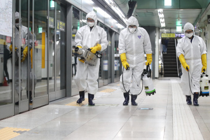 Workers wearing protective gear spray disinfectant as part of preventive measures against the spread of the COVID-19 coronavirus, at a subway station in Seoul on February 28, 2020. - K-pop megastars BTS on February 28 cancelled four concerts they were due to hold in Seoul in April, their agency said, as the coronavirus outbreak spreads in South Korea. The country has so far confirmed more than 2,000 cases of the novel coronavirus, by far the largest national total outside China, the origin of the disease. (Photo by - / YONHAP / AFP) / - South Korea OUT / REPUBLIC OF KOREA OUT  NO ARCHIVES  RESTRICTED TO SUBSCRIPTION USE