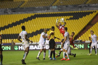 Esteban Dreer, golero de Liga de Portoviejo, intenta contener un balón en medio del acecho de los jugadores de Barcelona. Como fondo, las solitarias graderías del Monumental debido a la prohibición del ingreso de hinchas.