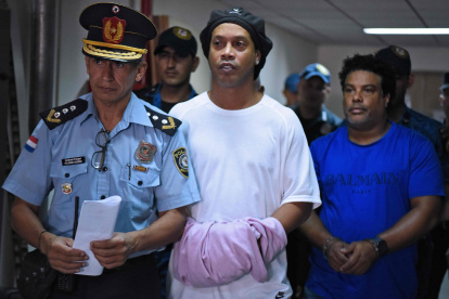 Ronaldinho (C) y su hermano, Roberto Assis (d) fueron detenidos el viernes y el sábado se les dictó orden de prisión. Permanecen en el edificio de una función judicial.