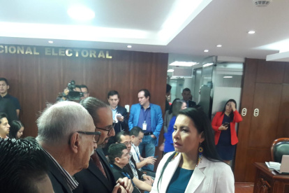 La presidenta del CNE, Diana Atamaint conversa con Pablo Dávila en la sesión que validó las firmas