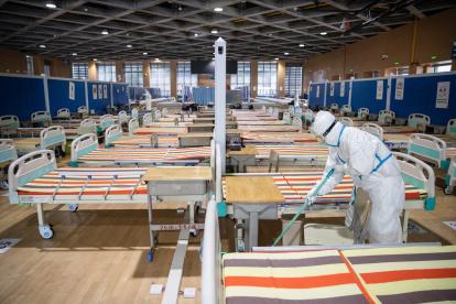 WUHAN. Personal sanitario limpia el piso en un hospital temporal establecido para tratar a las personas con el coronavirus COVID-19, después de que todos los pacientes fueron dados de alta.