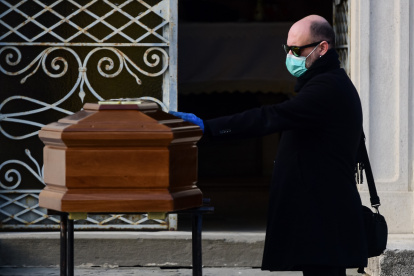 A man touches the coffin of his mother during a funeral service in the closed cemetery of Seriate, near Bergamo, Lombardy, on March 20, 2020 during the country"s lockdown aimed at stopping the spread of the COVID-19 (new coronavirus) pandemic. (Photo by Piero Cruciatti / AFP)