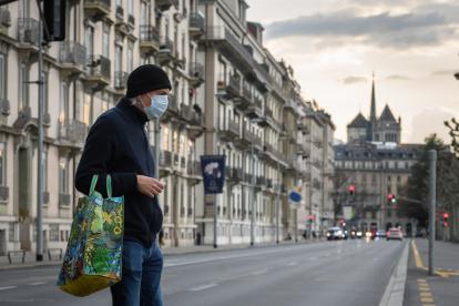 A man wearing a face mask uses a pedestrian crossing in front of Saint-Pierre Cathedral in Geneva on March 20, 2020, as the Swiss government further tightened measures against COVID-19, but said it would not follow other countries in ordering full confinement. (Photo by Fabrice COFFRINI / AFP)
