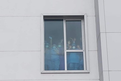 Los galenos a través de una ventana de la casa de salud, cubiertos de mascarillas y la protección requerida para su área, levantaron las manos en señal de victoria.