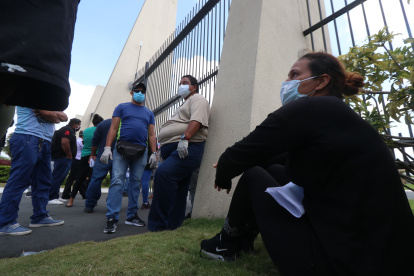 Personas usan mascarillas en el exterior de un cementerio de Guayaquil  a la espera de información de sus familiares fallecidos