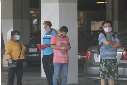 Personas toman sus precauciones al salir de sus casas para comprar víveres.