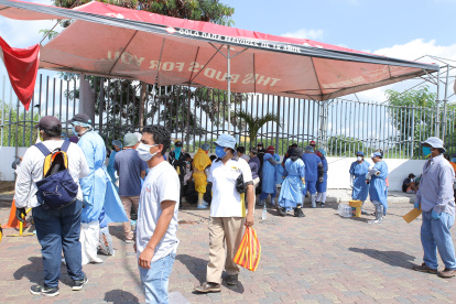 Ciudadanos en el exterior del hospital Guasmo Sur, uno de los centros de tratamiento del COVID-19, usan mascarillas como medida de prevención.