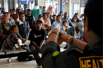 Un funcionario muestra los procedimientos de lavado de manos a los pasajeros que esperan en el puerto de Tenau en Kupang, Indonesia.