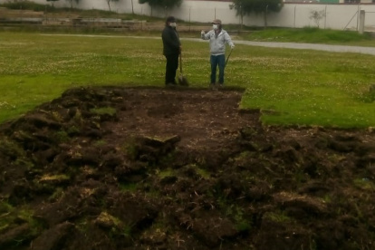 El conserje y el presidente de la liga reparan la cancha, maltratada por las lluvias.
