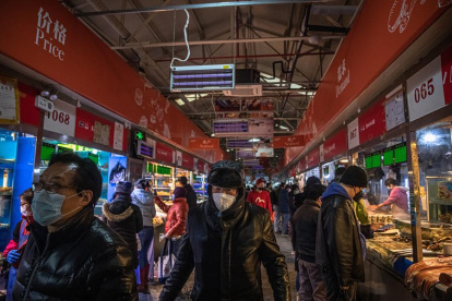 Las personas que usan máscaras protectoras visitan un mercado en Beijing, China