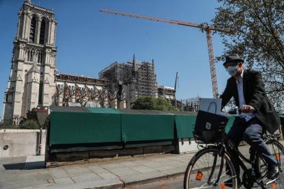 Paris (France), 09/04/2020.- A man wearing a protective facial mask rides his bicycle by the Notre Dame Cathedral, in Paris, France, 09 April 2020. France is under lockdown in an attempt to stop the spread of the SARS-CoV-2 coronavirus causing the COVID-19 disease. A year ago, on 15 April 2019, the 850-year-old Notre-Dame Cathedral of Paris suffered a devastating fire. Some 500 firefighters managed to prevent the entire cathedral from being reduced to ashes, although its celebrated spire has been destroyed. (Incendio, Francia) EFE/EPA/MOHAMMED BADRA