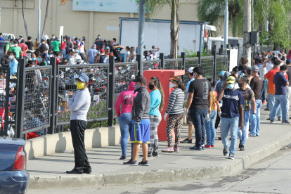 Los ciudadanos siguen aglutinándose en los exteriores de supermercados para abastecerse de víveres. Usan mascarillas, pero no respetan la distancia social.