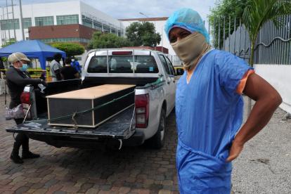 Un hombre se pone un traje protector fuera de la morgue del Hospital General Guasmo Sur para identificar a su pariente que murió del coronavirus.