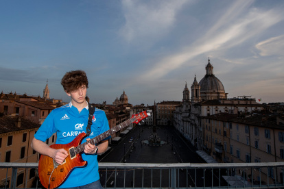 Jacopo Mastrangelo plays the guitar from his terrace overlooking Piazza Navona in Rome  on April 16, 2020, during a lockdown in Italy to curb the spread of the COVID-19 pandemic, caused by the new coronavirus. (Photo by Tiziana FABI / AFP)