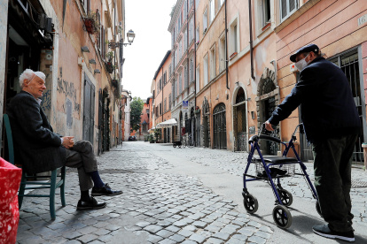 Ancianos protegidos con mascarillas conversan en el barrio de Trastevere, en Roma, Italia, este sábado. Varias regiones del sur de Italia han pedido mantener las restricciones de movimiento para contener la pandemia, después de que el norte, la zona más afectada por el coronavirus, esté presionando al Gobierno para acelerar la reapertura del país. EFE/Riccardo Antimiani