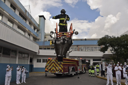 Fireman Henry Garcia stands on the top of a fire engine"s ladder from where he plays the trumpet to lift the spirits of personnel of the health sector and patients during the novel coronavirus COVID-19 pandemic, at the emergency door of the Carlos Andrade Marin Hospital in Quito, on April 18, 2020. (Photo by Rodrigo BUENDIA / AFP)