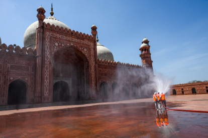 Municipal workers spray disinfectant at the main entrance of the Badshahi mosque ahead of the Muslim holy month of Ramadan during a government-imposed nationwide lockdown as a preventive measure against the COVID-19 coronavirus, in Lahore on April 22, 2020. -  (Photo by ARIF ALI / AFP)
