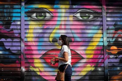 Una mujer con tapabocas es vista en Sao Paulo. Funcionarios desinfectan las calles de Paraisopolis, una de las mayores favelas de la ciudad.