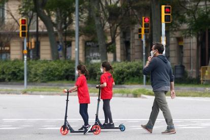 Un hombre y sus dos hijas caminan por una calle de Barcelona este lunes, segundo día en el que los menores de 14 años pueden salir a la calle una hora tras una cuarentena de 44 días por la pandemia de coronavirus.