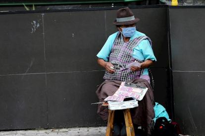 Una mujer con tapabocas vende lotería en las calles de Quito (Ecuador).