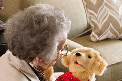 Fotografía cedida por el Departamento para Asuntos de la Tercera Edad de Florida (DOEA) donde se muestra a una anciana mientras disfruta un momento de compañía con un perro robótico de la empresa Joy for All.