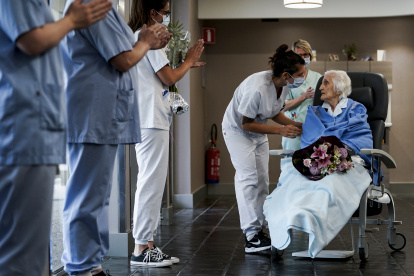 Medical workers clap as Belgian 100 year-old patient Julia Dewilde leaves the Bois de l"Abbaye hospital (CHBA) in Seraing, after being succesfully treated for COVID-19, the disease caused by the novel coronavirus, on April 29, 2020. (Photo by Kenzo TRIBOUILLARD / AFP)