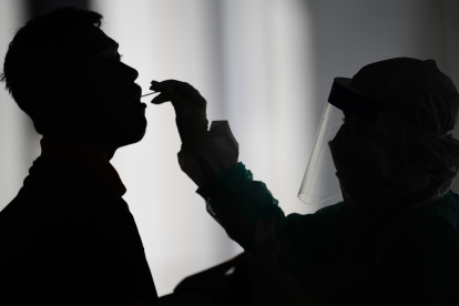 A health worker (R) uses a swab to collect a sample for COVID-19 coronavirus testing from a man in Gombak on the outskirts of Kuala Lumpur on April 22, 2020. (Photo by Mohd RASFAN / AFP)