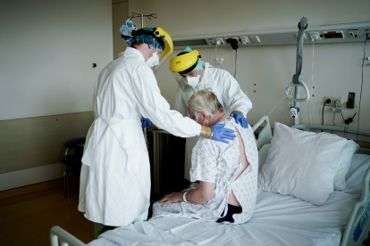 Physiotherapists and members of the medical staff visit a patient at the "middle care" unit for the COVID-19 infected patients at the Erasme Hospital in Brussels, on April 30, 2020 during a lockdown in the country to stop the spread of the novel coronavirus. (Photo by Kenzo TRIBOUILLARD / AFP)